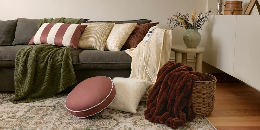 Living room with sofa, cushions, throws, woven basket, and patterned rug.