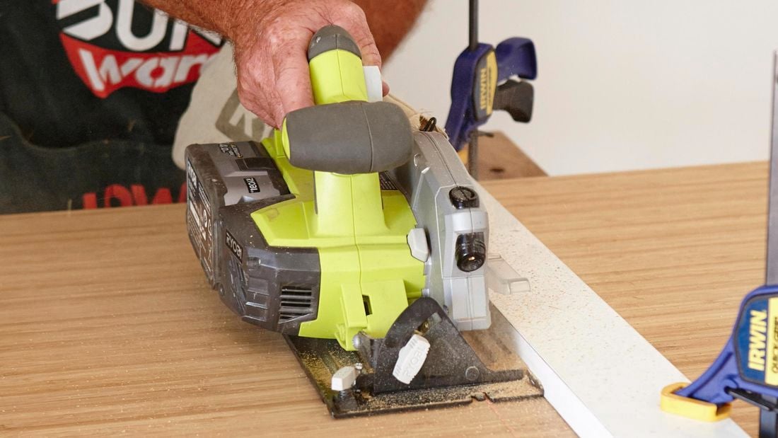 Person using saw to cut through bamboo benchtop.