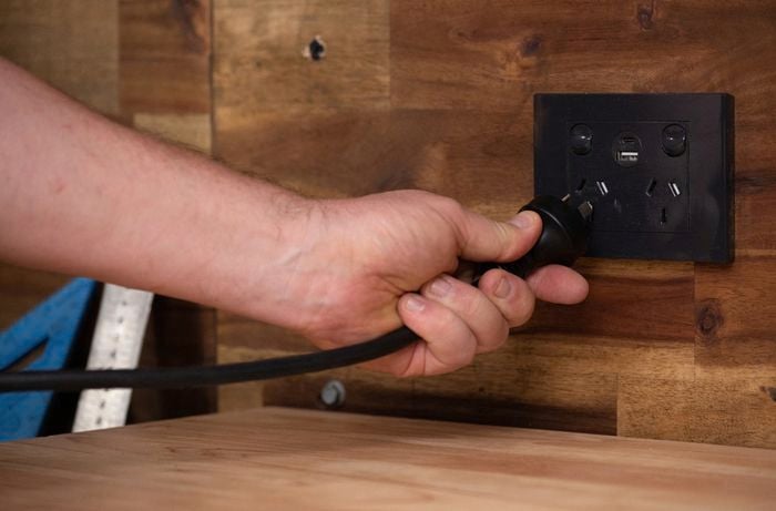 A person plugging in a stick welder electrical cord into a powerpoint.