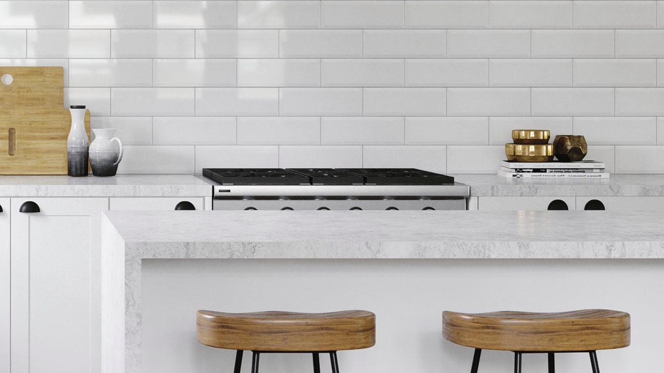 Kitchen with white benchtops, marble benchtop and white tile splashback.