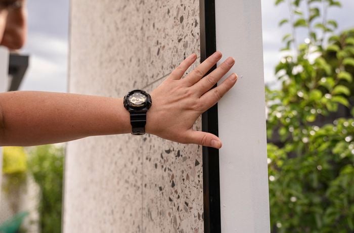 A person touching the tile trim.