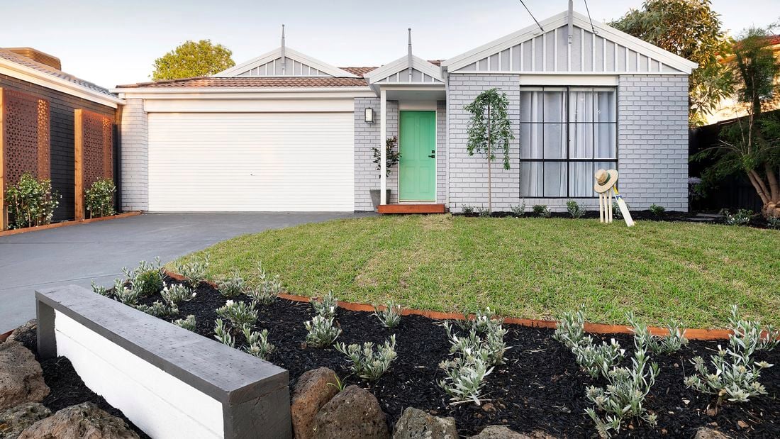 Renovated front yard with grey exterior, freshly laid turf and garden.