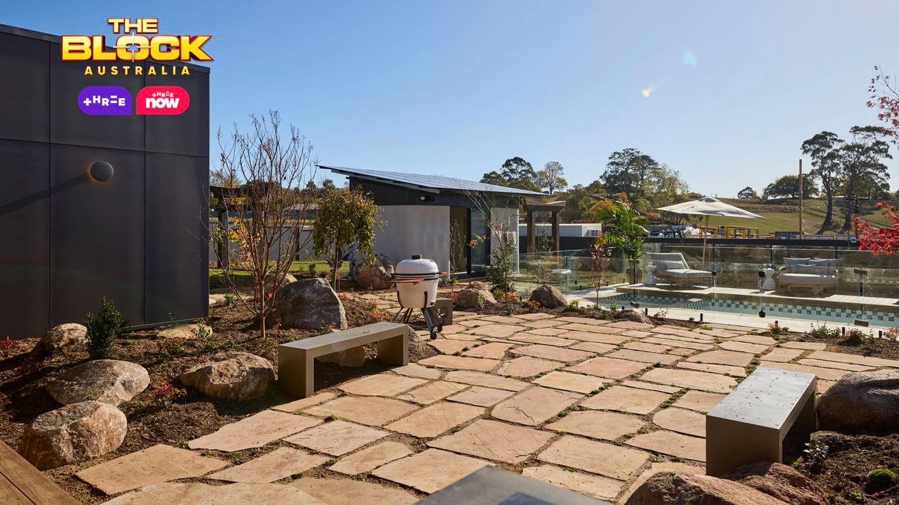 The backyard with a paved area, a pool, an outdoor room and trees in it.