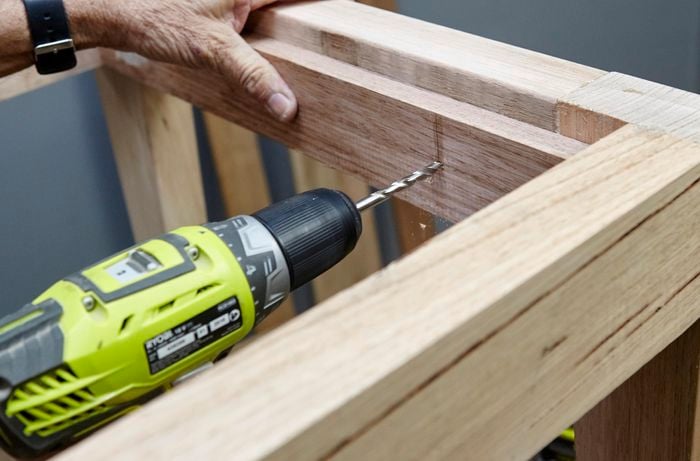 Holes being drilled into the subframe of a wooden table for later screwing into place