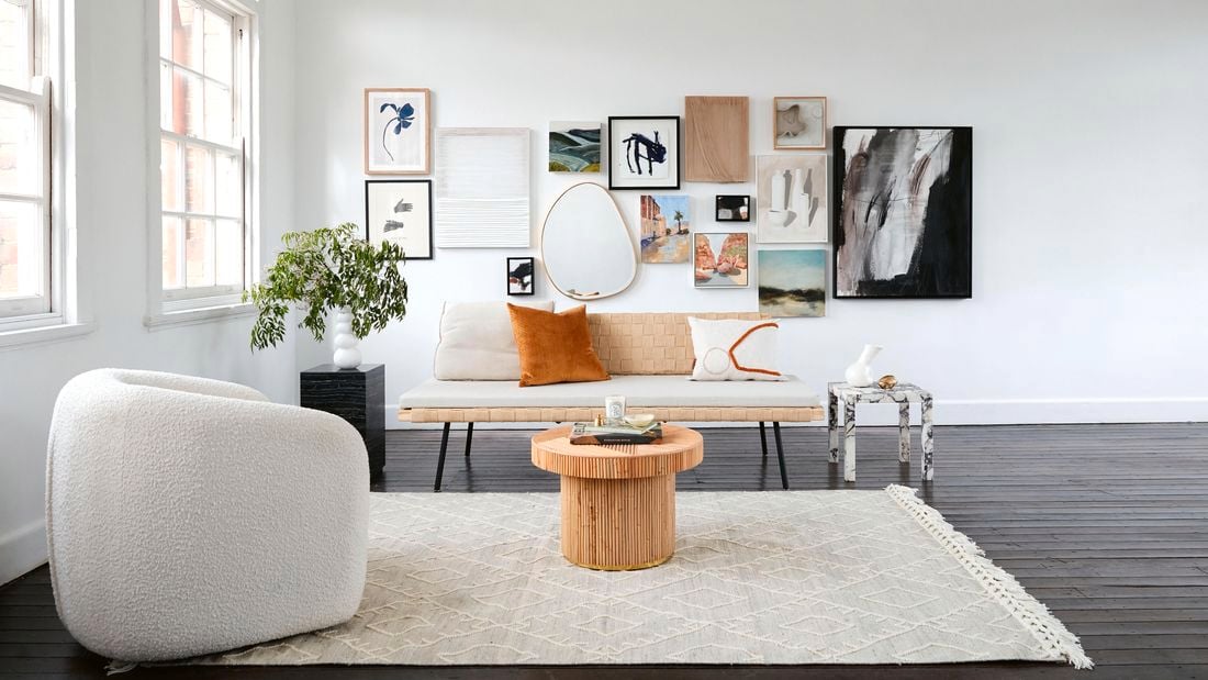 Lounge room with carpet, single chair, couch, indoor plant, decor n walls and central and side tables.