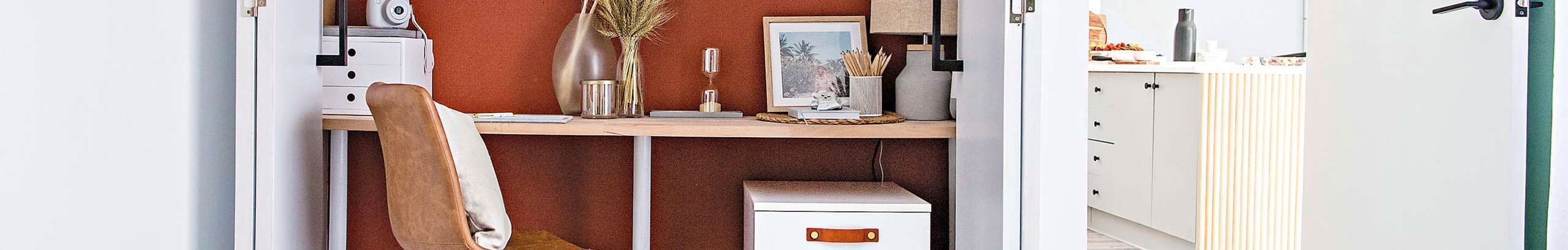 Home office set within a cupboard with orange walls and a wheeled chair