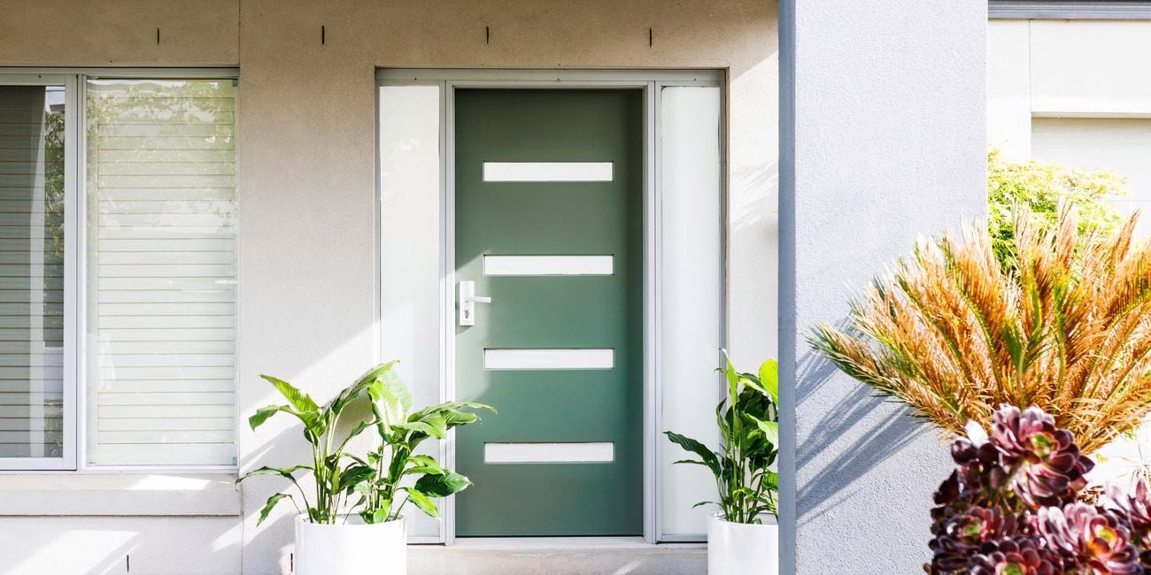 Freshly painted green front door with two potted plants either side.