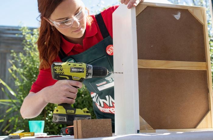 Woman drilling a hole in the front of a drawer