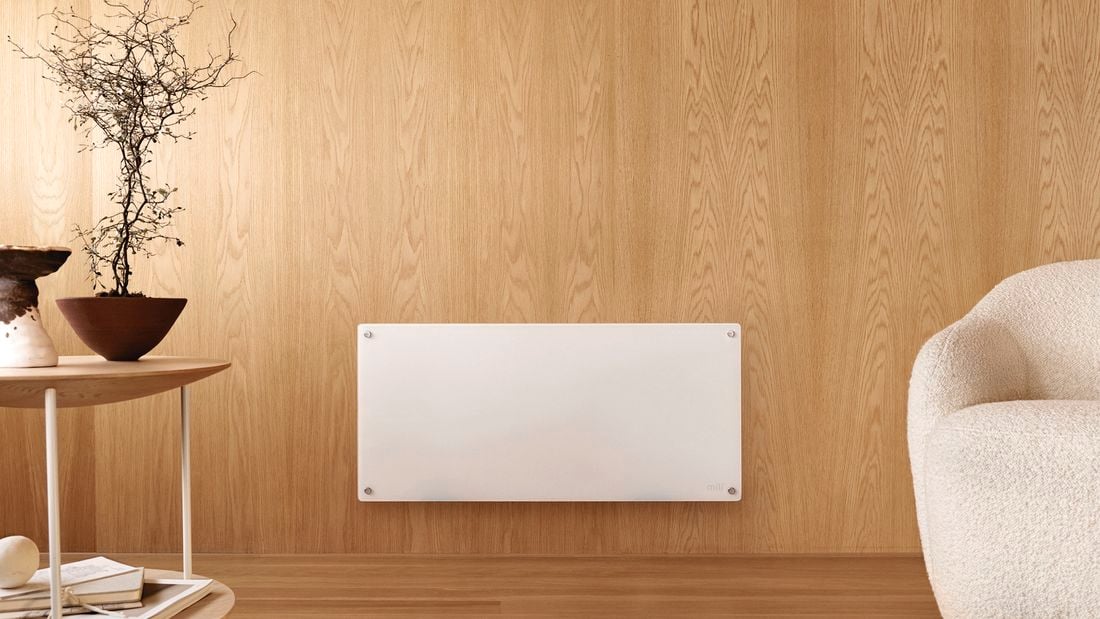 White panel heater mounted onto the bottom of a cream wall in a living room area]