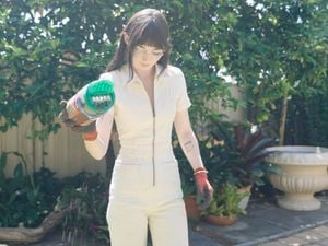 Person with gardening gloves holding Yates Lawn Shaker.