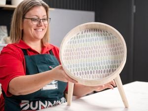 A Bunnings Team Member holding a mosaic side table