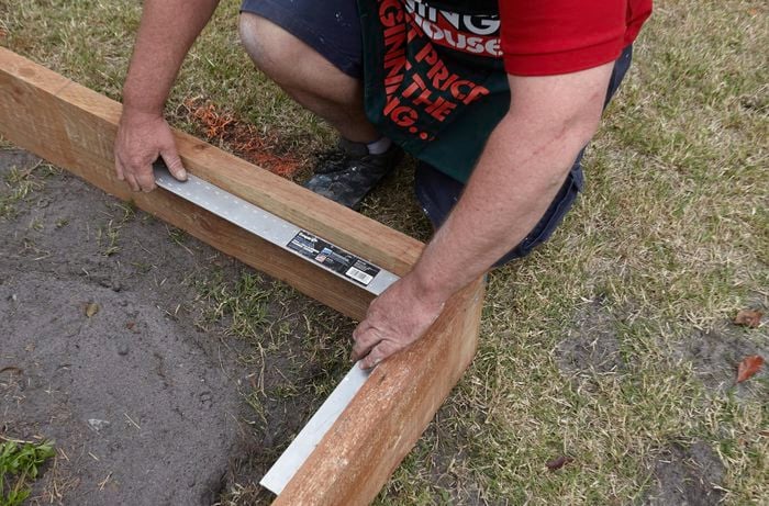 A square rule being used to ensure the correct placement of garden bed sleepers