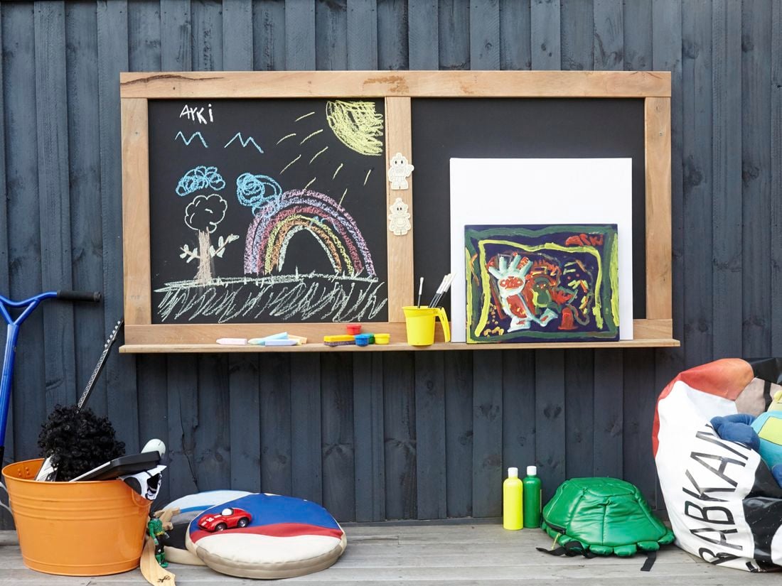 Children's blackboard with chalk drawings of trees and rainbows on it