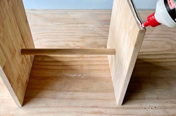 Two panels of timber attached by a dowel, with glue being applied to the edges