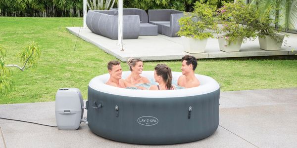 Four people enjoying a Bestway inflatable spa near a pool
