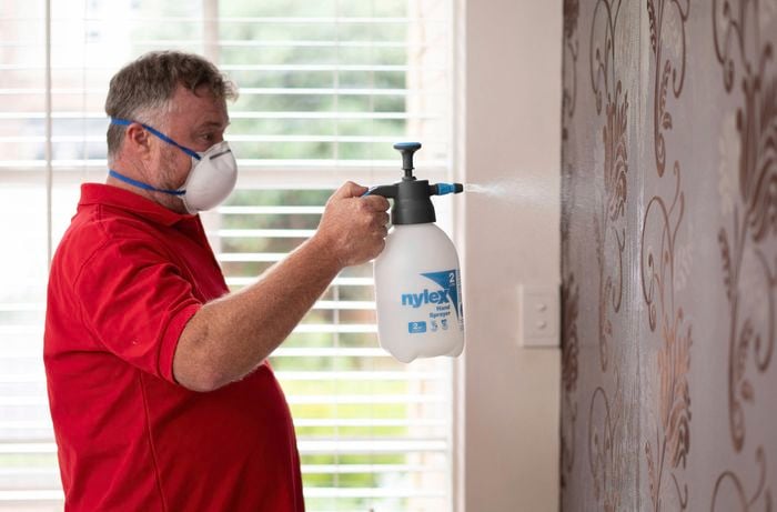 Applying wallpaper remover with sprayer.