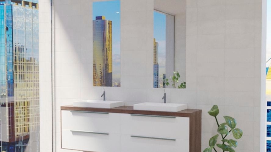 Bathroom with two mirrors along with two wash basins with two taps and drawers underneath, plant and white wall tiles.