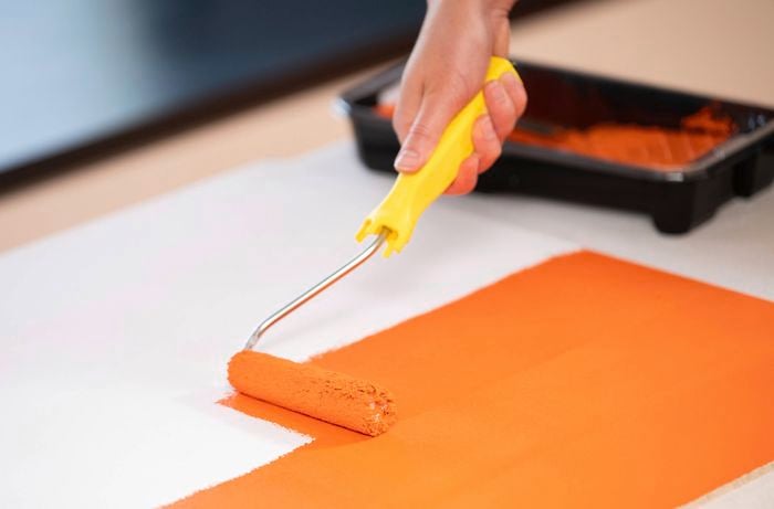Applying a bright orange base coat with a paint roller