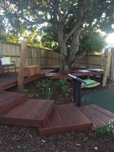 A multi-tier deck leading up to and around a tree in a backyard