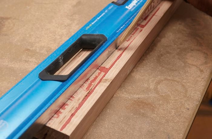 Person marking timber using pencil and spirit level