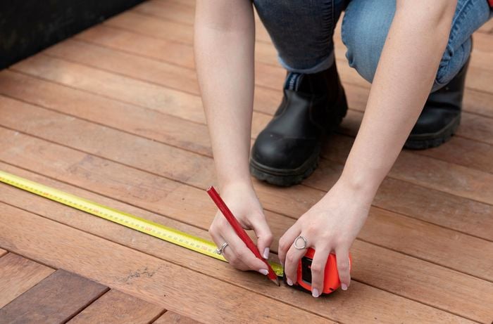 Person using tape measure to make marks on deck.