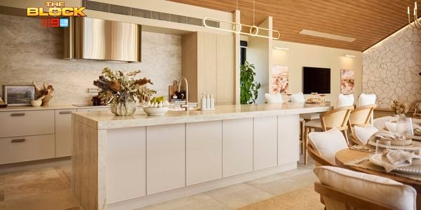 Modern kitchen with marble island, stone feature wall, and dining table.