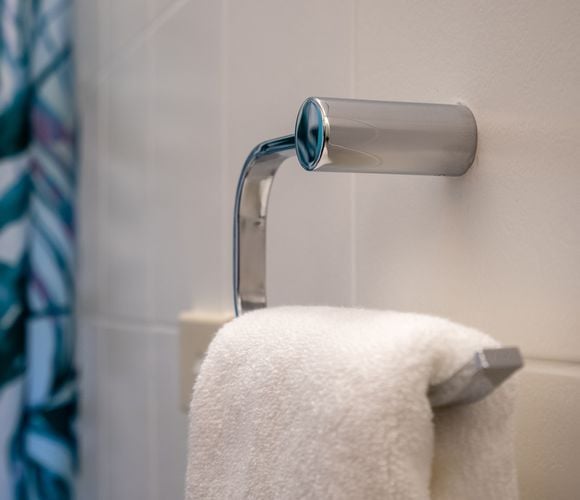 Chrome C-shaped hand towel holder with white towel attached