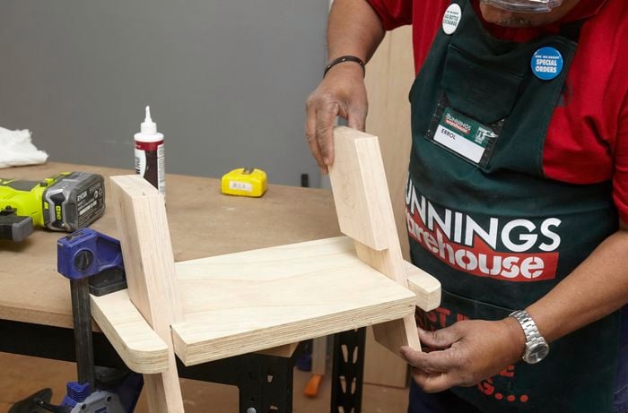 Person placing legs for DIY wooden step stool into step.