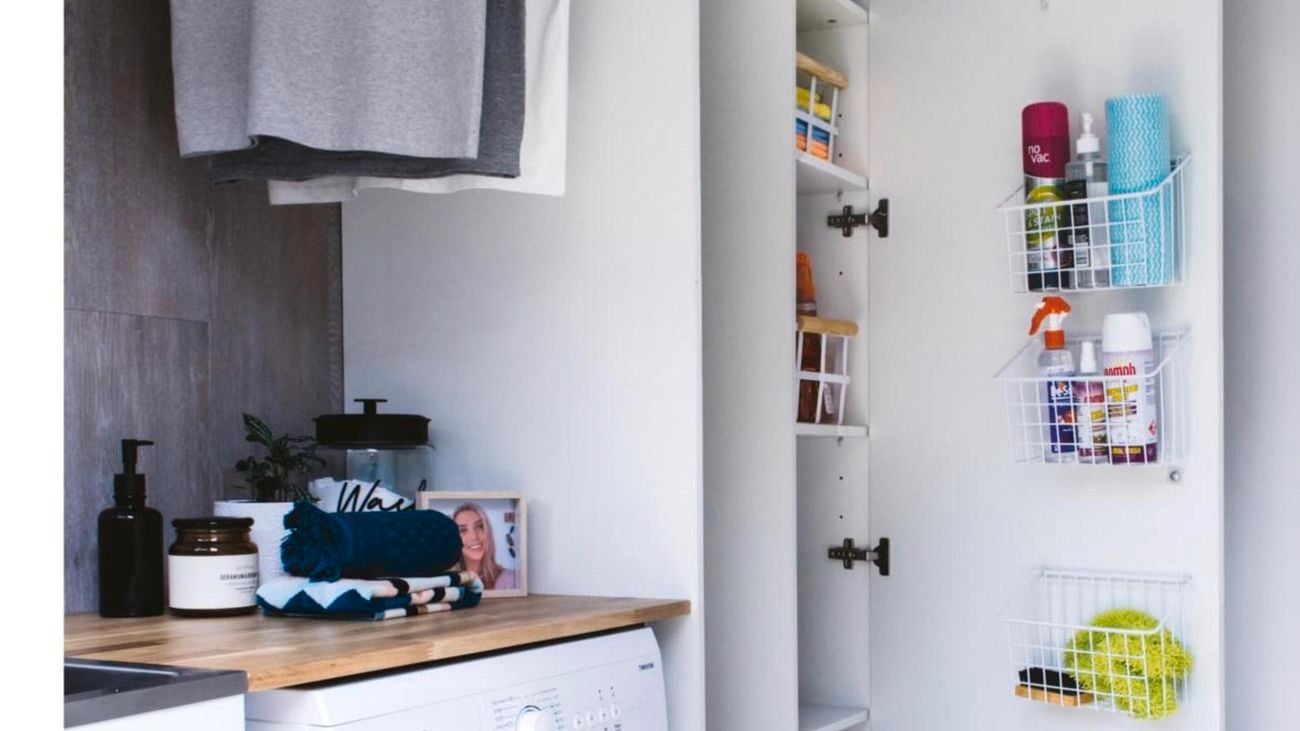 Laundry with washing machine and cupboard with storage containers on inside of door