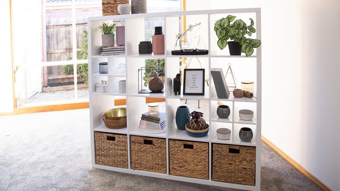 Cube unit with woven boxes, plants and other decorative items.