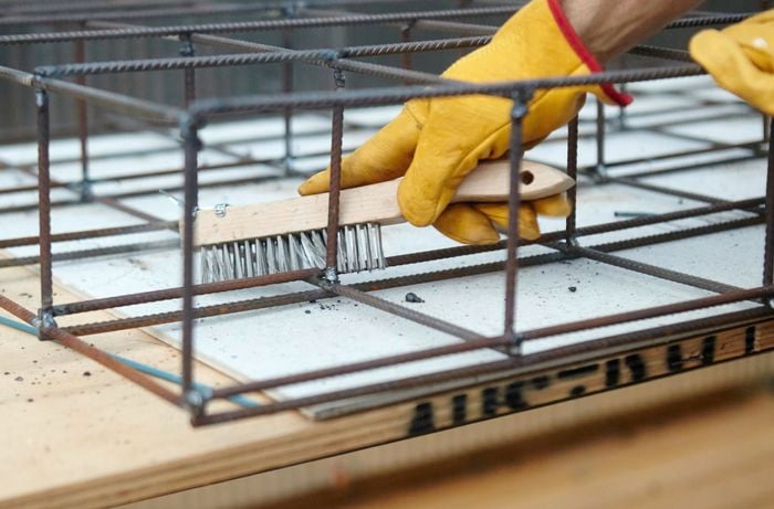 A wire brush being used to clear away slag from a weld in a wire mesh frame