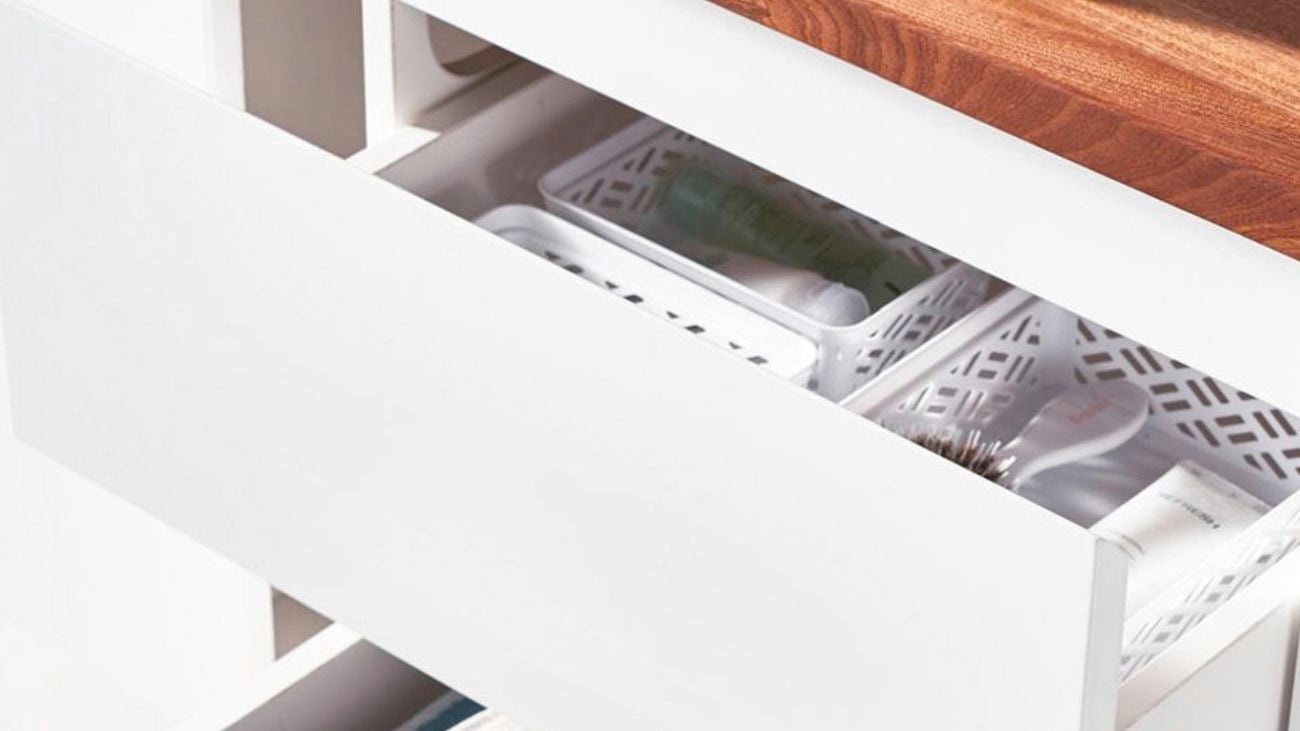 A white bathroom cabinet with a wooden countertop. Two drawers are pulled out showing basket storage and folded towels.