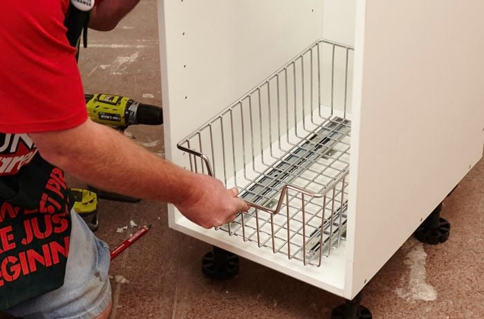 Person placing basket in bottom and centre of cabinet