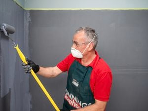 Bunnings team member wearing a mask while applying membrane to a wall