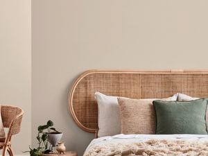 Bedroom with beige walls, a bed, a side table and a chair in it.