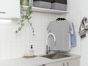 Laundry bench with tiled wall and hanging cloths