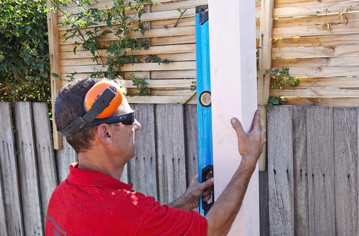 A person checking a timber post with a spirit level