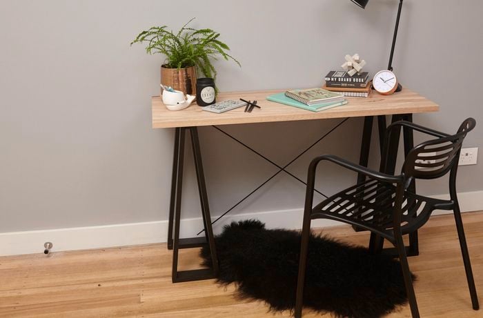 A timber trestle table on black A-frame legs