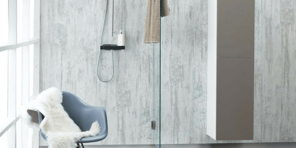 A bathroom with large, stone-look wall panels and a chair