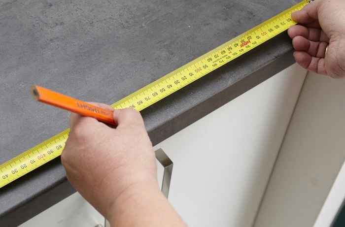 Using a tape measure to mark the centre of the benchtop.