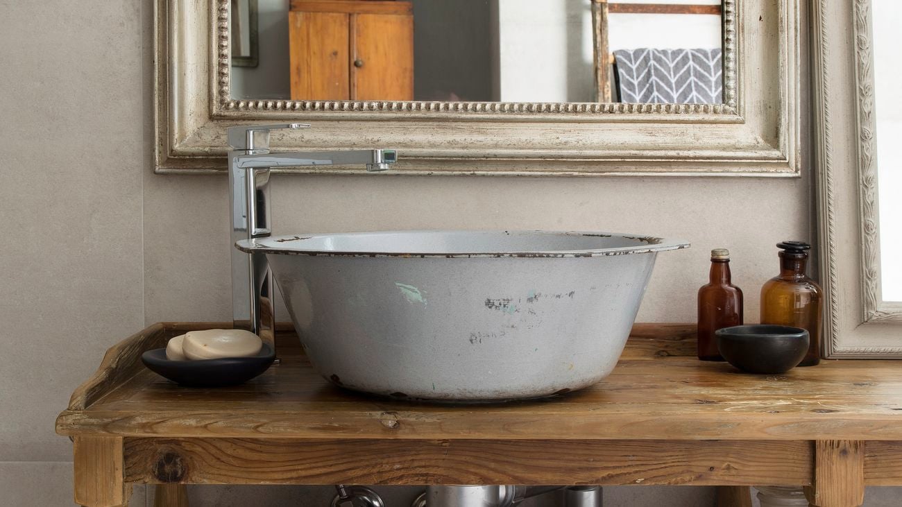 Bathroom with a rustic wooden table with a silver metal sink on top and large rectangle mirror above.