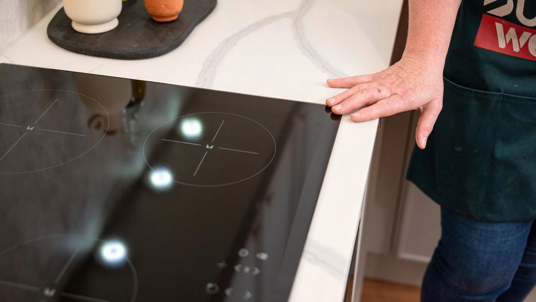 A person keeping his hand on an electric cooktop.