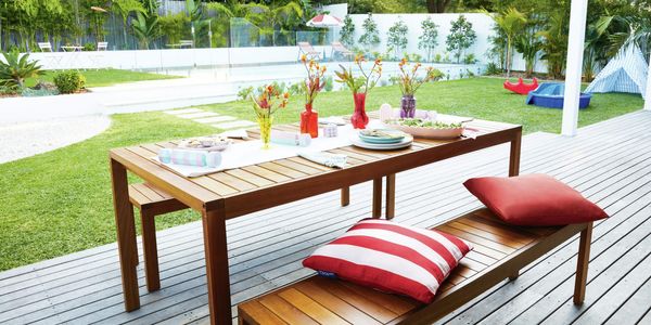 Outdoor decorated setting on a deck with a pool in backyard.