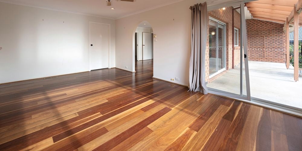 Empty room with wooden floorboards and fan on the ceiling