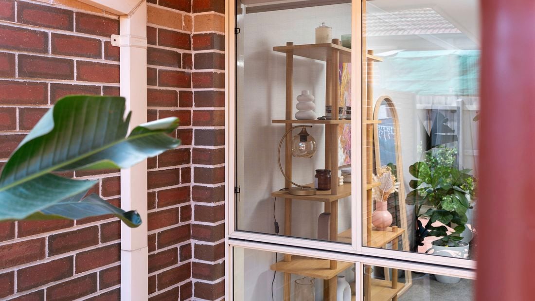 An image of a flyscreen has been installed on a window, with the interior showcasing shelves of decor and plants. ]    