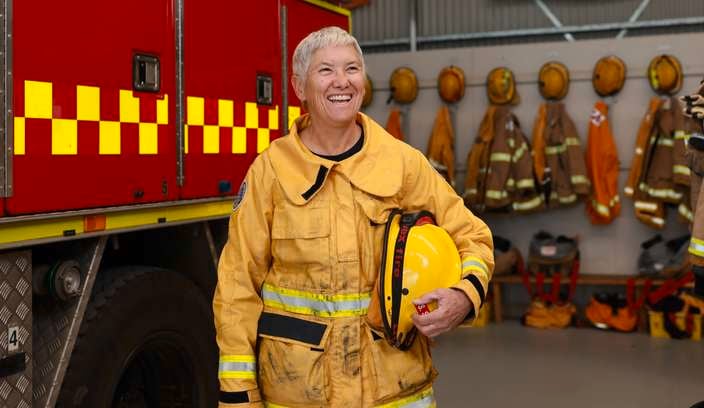 A lady in a CFA uniform standing next to a fire engine.