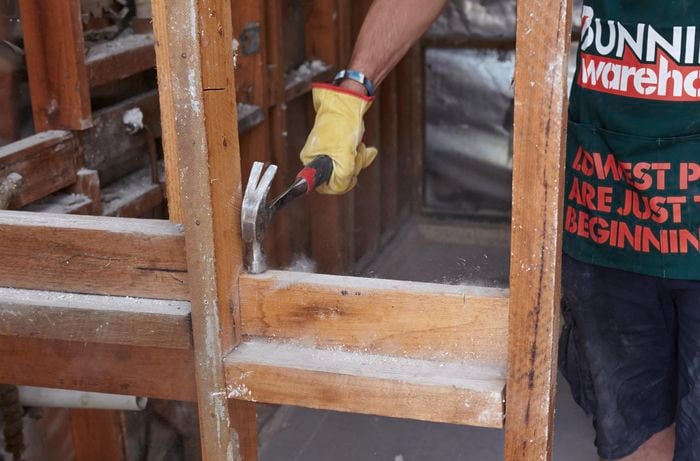 A hammer being used to strike the noggins clear of a stud wall