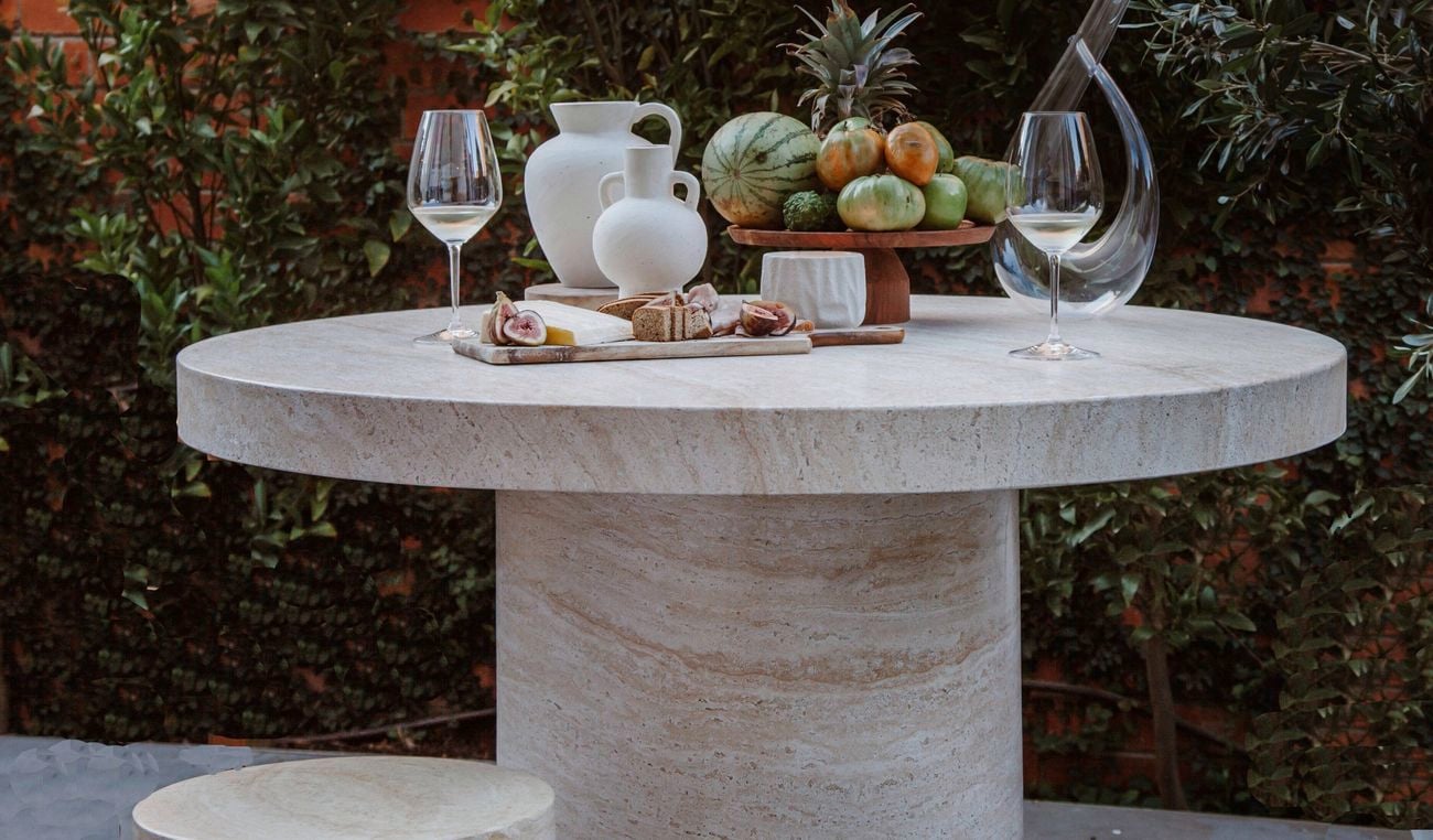 Outdoor table in front of a brick wall and plants