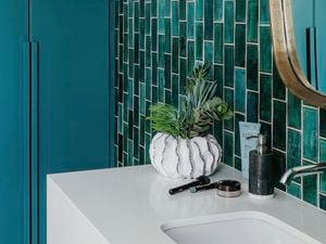 Bathroom with basin, artificial flowers, soap and mirror.