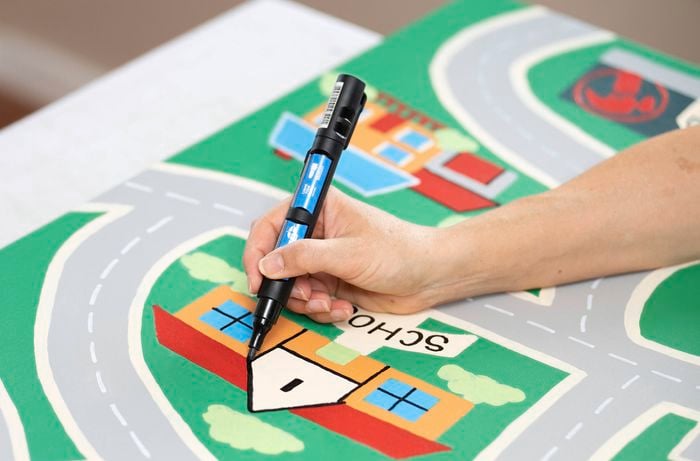  A person is drawing simple building shapes like a school, shop or café with a paint pen 